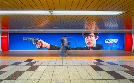 Téléchargez les photos : Tokyo, Japon - 28 avril 2024 : Affiche du film Netflix "City Hunter" ou "Nicky Larson" sur le mur d'un métro Shibuya mettant en vedette l'acteur japonais Ryohei Suzuki dans le rôle de Ryo Saeba tenant un pistolet magnum. - en image libre de droit