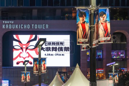 Téléchargez les photos : Tokyo, Japon - 28 avril 2024 : Lampadaires illuminant la nuit de Kabukicho avec des fanions mettant en vedette l'acteur japonais Ryohei Suzuki dans le rôle de Ryo Saeba interprété par Tsukasa Hj dans le film de Netflix City Hunter. - en image libre de droit