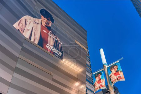 Foto de Tokyo, Japón - 28 abr 2024: Vista de bajo ángulo en una fachada y una lámpara de calle de Kabukicho con banderines con el actor japonés Ryohei Suzuki como Ryo Saeba alias Nicky Larson en la película de Netflix "City Hunter". - Imagen libre de derechos