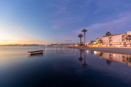 Photo for View of the Espejo beach in Los Alcazares, Region of Murcia, Spain, at sunrise and with a boat and palm trees in the background - Royalty Free Image