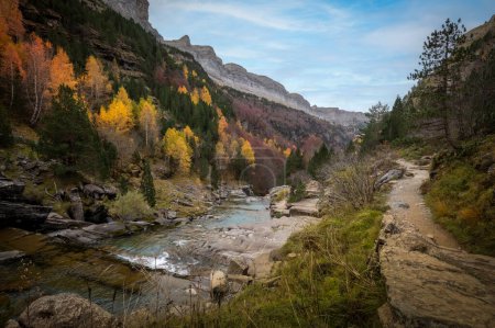 Photo for Autumn landscape in the Ordesa y Monte Perdido national park in the Pyrenees, in Huesca, Spain, where you can see a path for hikers and a blue river - Royalty Free Image