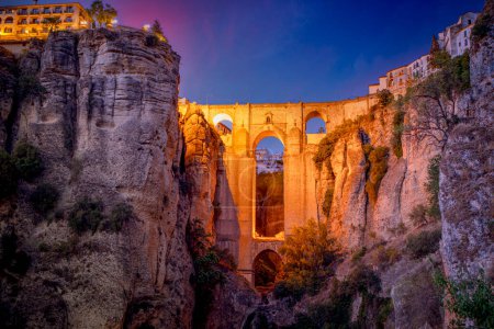 Téléchargez les photos : Vue spectaculaire sur le nouveau pont de Ronda, Malaga, Espagne, illuminé au crépuscule depuis la partie inférieure de la ville - en image libre de droit