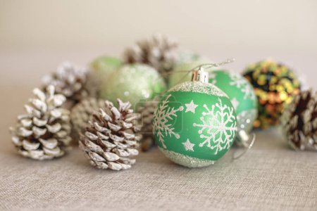 Foto de Bodegón de Navidad con conos de pino pintados de blanco y bolas de Navidad verdes en la mesa con luz suave y blanquecina - Imagen libre de derechos