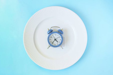 Intermittent fasting concept. Clock lay in the plate. Weight loss plan