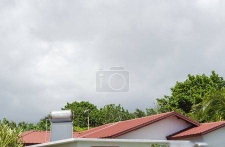 Foto de Una unidad de calentador de agua solar con un tambor y panel solar se instala en un techo de la casa roja. - Imagen libre de derechos