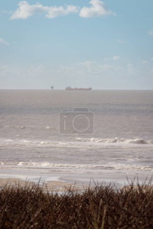 Téléchargez les photos : Dunes sur la plage de Katwijk, Pays-Bas, avec des navires et des éoliennes à l'horizon - en image libre de droit