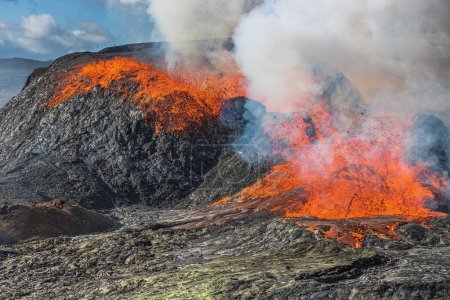 Foto de Volcán activo en Islandia. Erupción con flujo de lava desde un cráter volcánico en la península de Reykjanes. Brillante lava caliente con una pequeña fuente. vapor ascendente del cráter volcánico - Imagen libre de derechos