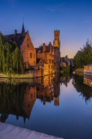 Photo for Bruges in the evening. Rosary Quay canal in the old town of the Hanseatic city. Reflections on the water surface with historic buildings. Illuminated old merchant houses in summer - Royalty Free Image