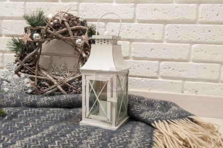 Photo for Winter background with a plaid, a lantern and a Christmas wreath against a white brick wall - Royalty Free Image