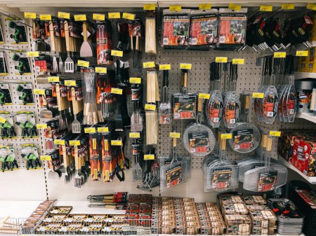 Foto de Turning paddles, large forks and grill grates hang on shelves in a supermarket. High quality photo - Imagen libre de derechos