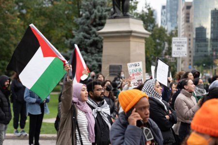 Téléchargez les photos : Toronto, Canada - 18 octobre 2023 : Une foule se rassemble pour une manifestation pacifique, avec une voix principale amplifiée par un mégaphone. Photo de haute qualité - en image libre de droit