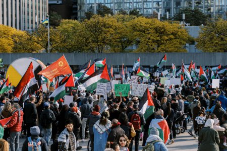 Foto de Toronto, Canadá - 28 de octubre de 2023: Diversa multitud en un mitin contra la guerra protesta por la agresión israelí en Gaza, mostrando varias banderas y carteles en medio de un entorno urbano. Foto de alta calidad - Imagen libre de derechos