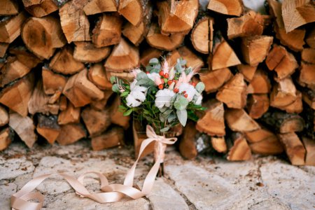 Photo for Bridal bouquet tied with a beige ribbon stands near the woodpile. High quality photo - Royalty Free Image