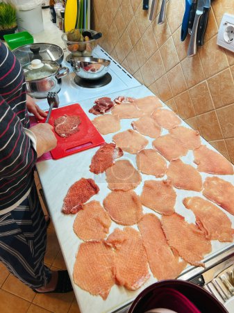 Photo for Housewife makes chops of meat with a hammer on a cutting board on the table. High quality photo - Royalty Free Image