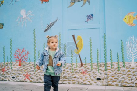 Photo for Little girl walks near a house painted with colorful drawings. High quality photo - Royalty Free Image