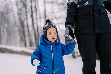 Photo for Little girl stands with her mouth open, holding her mother hand in a snowy forest. Cropped. High quality photo - Royalty Free Image