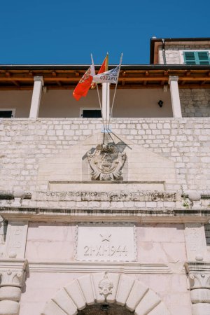 Photo for Flags fly on a flagpole above the coat of arms on the ancient sea gate. Kotor, Montenegro. High quality photo - Royalty Free Image