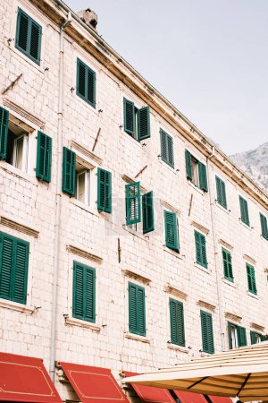 Foto de Fachada de piedra de un antiguo edificio de apartamentos con persianas verdes en las ventanas. Foto de alta calidad - Imagen libre de derechos
