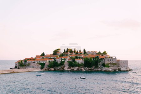 Foto de Pequeños barcos están amarrados cerca del istmo de la isla de Sveti Stefan. Montenegro. Foto de alta calidad - Imagen libre de derechos