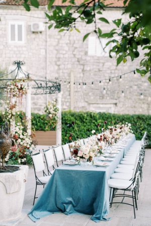 Téléchargez les photos : Ensemble table de fête avec des bouquets de fleurs dans la cour d'une ancienne maison. Photo de haute qualité - en image libre de droit