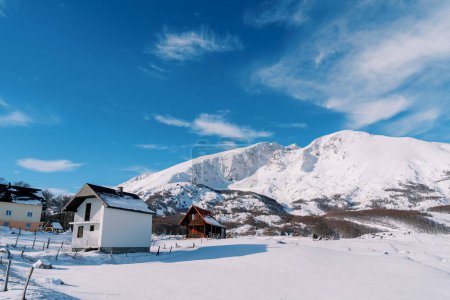 Two-storey cottages in a mountain village at the foot of snow-capped mountains. High quality photo