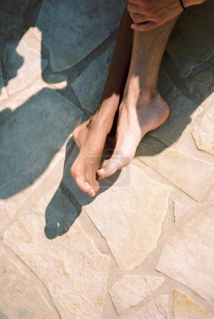 La jambe de l'homme touche la jambe de la femme assise sur une tuile au soleil. Découpé. Sans visage. Photo de haute qualité