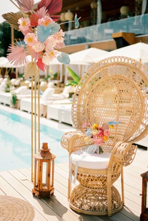 Bright wedding bouquet stands on a wicker armchair near the wedding arch. High quality photo
