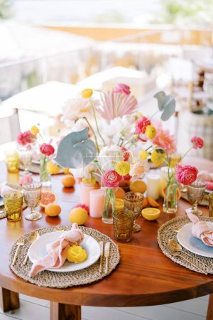 Foto de Las planchas con las servilletas anudadas sobre las esteras se sitúan sobre la mesa de fiesta con los colores de las flores. Foto de alta calidad - Imagen libre de derechos