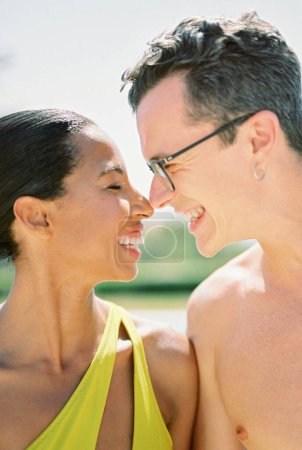 Smiling man and woman in a swimsuit touch their noses. Close-up. High quality photo