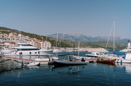 Inflatable motor boats stand next to yachts at the marina berths. High quality photo
