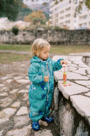 Photo for Little girl dipping a soap bubble stick into a bottle of liquid. High quality photo - Royalty Free Image