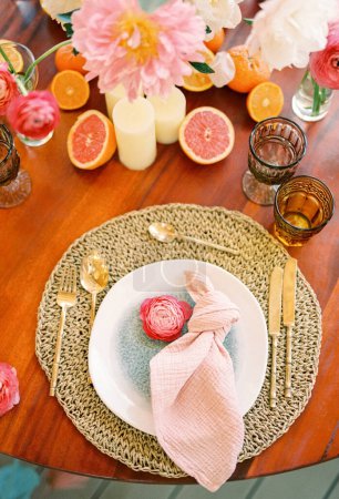 Foto de La flor rosada yace en un plato sobre una alfombra de mimbre en una mesa festiva. Foto de alta calidad - Imagen libre de derechos