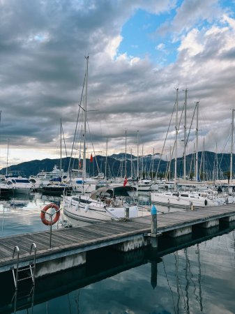 Sailing yachts stand at the pier against the backdrop of a mountain range. High quality photo