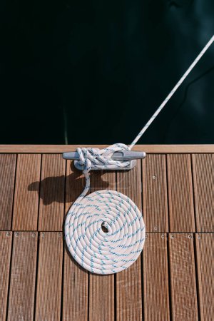 Um den Poller auf der Seebrücke ist ein weiß gestreiftes Seil gewickelt. Ansicht von oben. Hochwertiges Foto