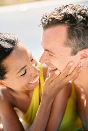 Laughing woman touches the cheek of laughing man while standing in a swimming pool. Portrait. High quality photo