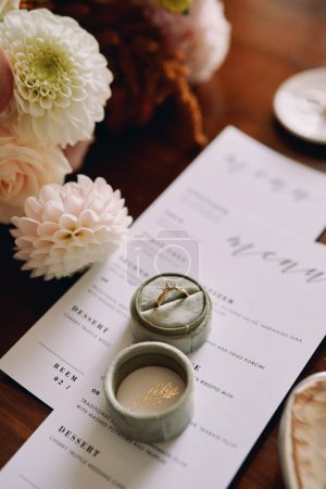 La bague de fiançailles dans une boîte se trouve sur un menu de vacances près des fleurs. Photo de haute qualité