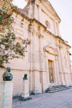 Floreciente adelfa y bustos en pedestales cerca de la Iglesia de la Natividad de la Virgen. Prcanj, Montenegro. Foto de alta calidad
