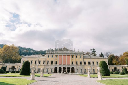 Park with statues in front of the ancient Villa Olmo with empty banners on the facade. Lake Como, Italy. High quality photo