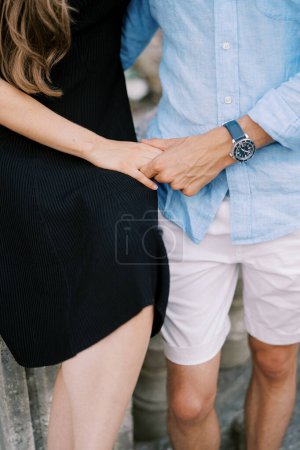 Mann und Frau stehen auf steinernen Stufen, umarmen sich und halten Händchen. Beschnitten. Gesichtslos. Hochwertiges Foto