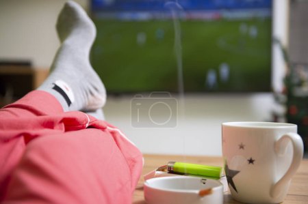 Photo for Watching a football game. Feet up in front of TV. Relaxed home atmosphere. - Royalty Free Image