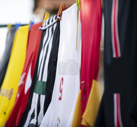 Bunte Kleider hängen zum Trocknen an einer Wäscheleine. Fußballtrikots