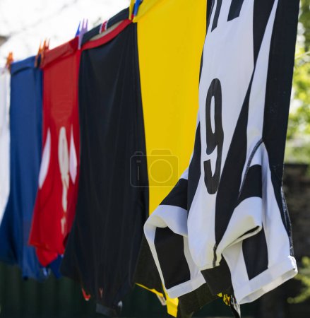 Colorful clothes hanging to dry on a laundry line. Football jerseys
