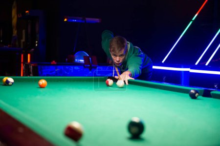 Handsome young man playing pool in pub 