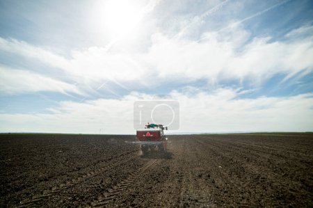 Tracteur épandant des engrais artificiels. Transports, agriculture.
