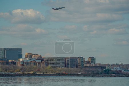 Foto de WASHINGTON DC, EE.UU. - 29 DE MARZO DE 2023 un avión jet está despegando del Aeropuerto Nacional Ronald Reagan. Edificios detrás del aeropuerto se ven en el fondo del río Potomac - Imagen libre de derechos