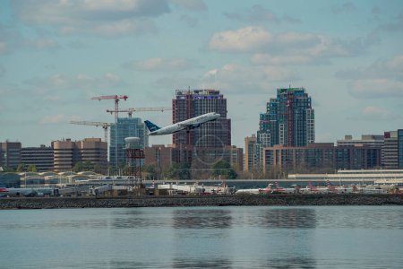 Téléchargez les photos : WASHINGTON DC, États-Unis - Le 29 mars 2023, un avion décolle de l'aéroport national Ronald Reagan. Bâtiments derrière l'aéroport sont vus en arrière-plan de la rivière Potomac - en image libre de droit