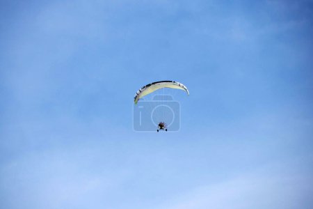 Photo for A Powered Motorized paraglider flying against the blue sky outdoor activity, extreme sports, sport of paragliding - Royalty Free Image