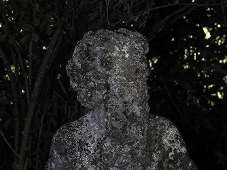 Una antigua estatua de un fauno en un detalle de jardín