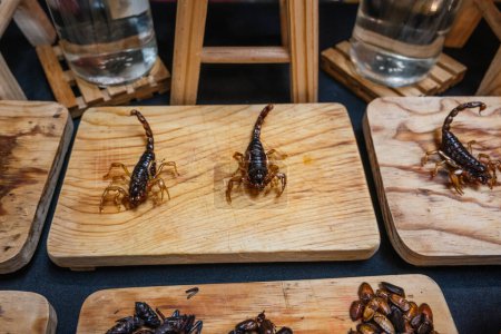 Foto de Escorpiones e insectos fritos, comida tradicional prehispánica mexicana, servidos en una tabla de madera. - Imagen libre de derechos