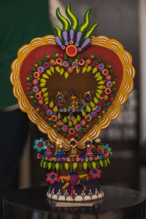 Colorful heart made of clay with a birth of Jesus in the central part, traditional Mexican crafts.